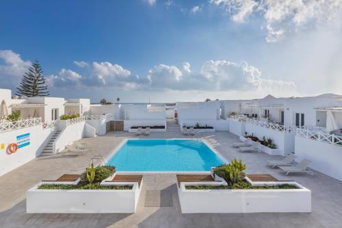 a villa with a swimming pool and white buildings at Flower Beach Suite 20 in Playa Honda