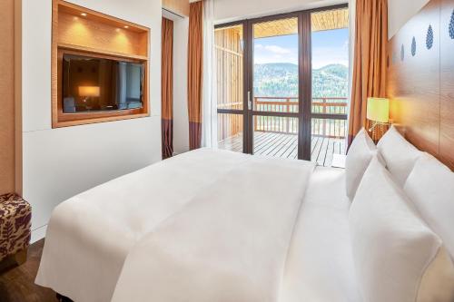 a bedroom with a large white bed with a large window at Radisson Blu Resort Bukovel in Bukovel