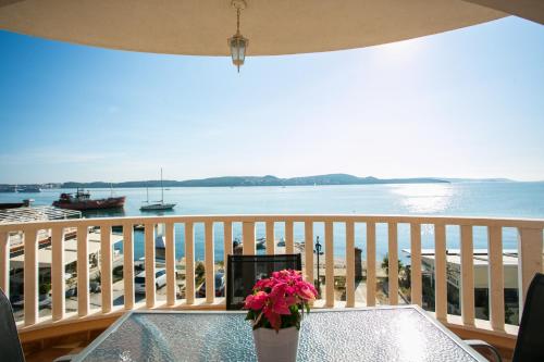 a table with a vase of flowers on a balcony at Kaja - right next to the beach in Trogir