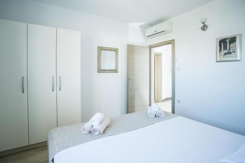 a bedroom with a white bed with towels on it at Kaja - right next to the beach in Trogir