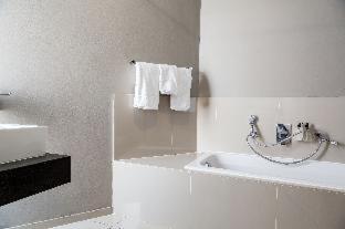 ein Badezimmer mit einer Badewanne, einem Waschbecken und Handtüchern in der Unterkunft Aquarius Luxury Suites in Bloubergstrand