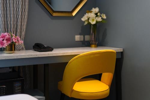 a yellow chair sitting next to a desk with flowers at The Mulberry Bangkok Khaosan Road in Bangkok