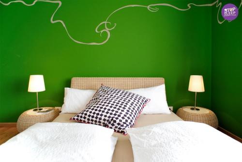 a green bedroom with a bed and two lamps at Stop & Sleep Udine in Udine