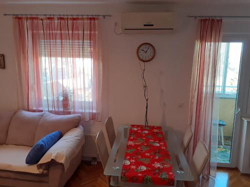 ein Wohnzimmer mit einem Sofa, einem Tisch und einer Uhr in der Unterkunft Apartman Mario in Osijek