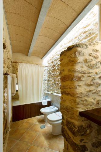 a stone bathroom with a toilet and a stone wall at Agroturismo Xarc in Santa Eularia des Riu