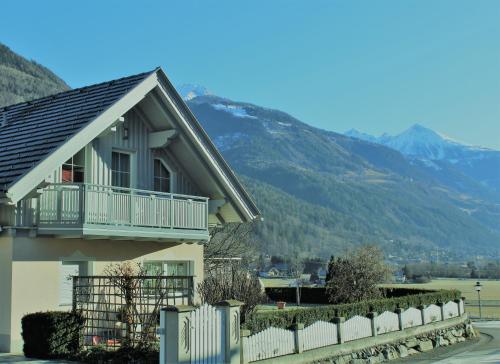 a house with a fence and mountains in the background at Ferienwohnung Daberer in Obervellach