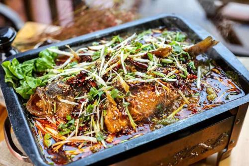 a dish of food in a pan on a table at Pingyao HongJingYuanGuesthouse in Pingyao