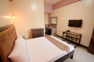 a bedroom with a bed and a desk and a television at RSG Microhotel in General Santos