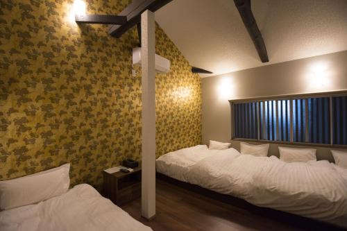 2 camas en una habitación con papel pintado de color amarillo en Nakamuraya Kyoto Enmachi Sakura, en Kioto