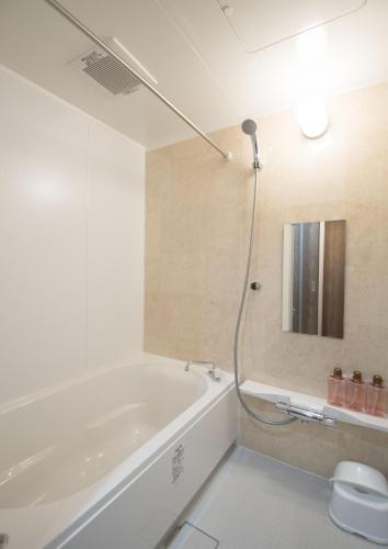 a white bathroom with a tub and a mirror at Nakamuraya Kyoto Enmachi Sakura in Kyoto