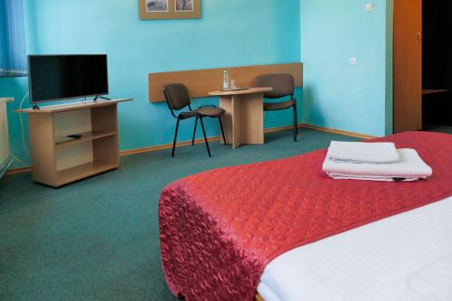 a hotel room with a bed and a tv and chairs at Hotel Chemik in Bydgoszcz