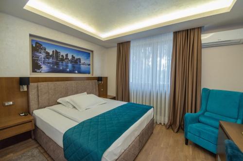 a hotel room with a bed and a blue chair at Hotel Park in Srebrenik