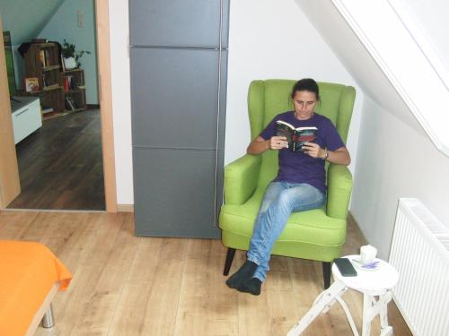 a man sitting in a green chair reading a book at Ferienhaus Grabenhansl in Stubenberg