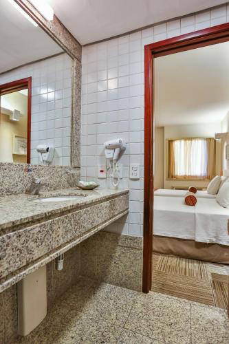a hotel bathroom with a bed and a mirror at Comfort Suites Brasília in Brasília