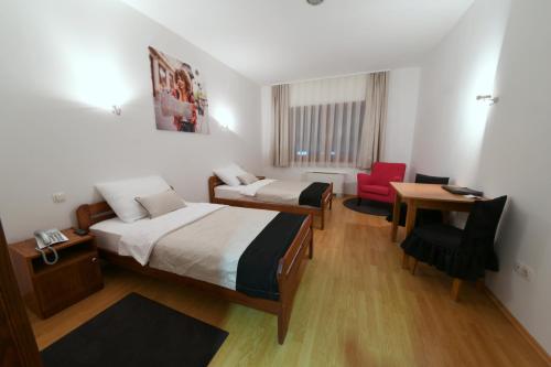Habitación con 2 camas, escritorio y silla. en Apartments & Rooms Krizevci, en Križevci