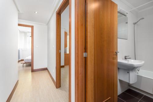 Un baño con lavabo y puerta de madera. en Balea 8 - Local Rentss, en Orio