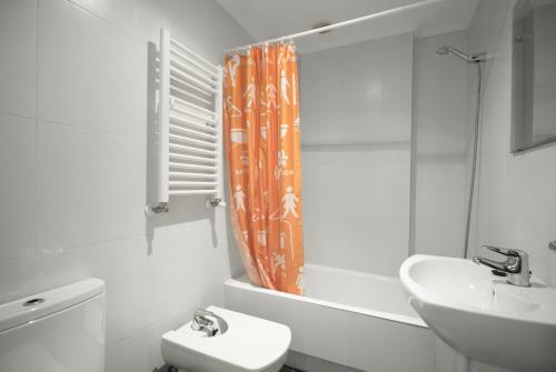 y baño con cortina de ducha naranja, aseo y lavamanos. en Balea 2 - Local Rentss, en Orio
