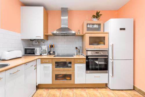 una cocina con electrodomésticos blancos y armarios de madera en Bergara - Local Rentss, en San Sebastián
