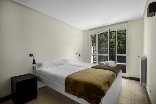 a white bedroom with a large bed and a window at Apartamento Balea VII in Orio