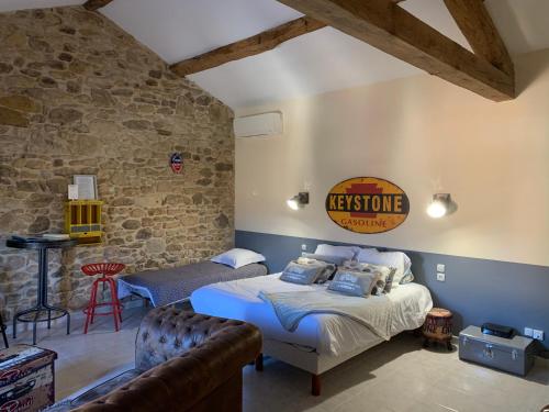 a bedroom with two beds and a stone wall at CHAMBRE D’HÔTES NATURE ET SAVEURS in Boutenac
