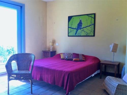 1 dormitorio con cama rosa, silla y ventana en Villa Soleanda, en Marsiliana