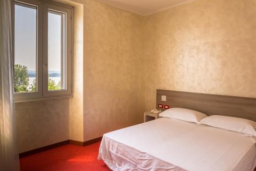 a bedroom with a white bed and a window at Hotel italia dormelletto in Dormelletto
