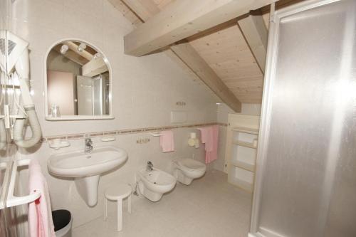 a bathroom with a sink and a toilet and a mirror at Hotel Villa Mozart in Pozza di Fassa