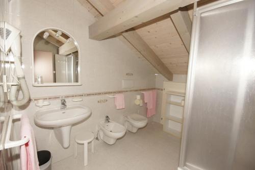 bagno con lavandino, servizi igienici e specchio di Hotel Villa Mozart a Pozza di Fassa
