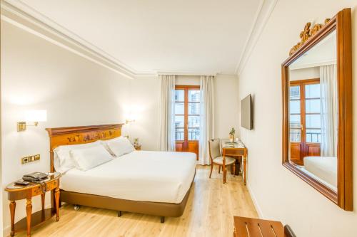 Habitación de hotel con cama y espejo en Sercotel Arenal Bilbao en Bilbao