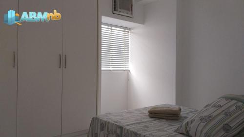 ein weißes Schlafzimmer mit einem Bett und einem Fenster in der Unterkunft Apto no Universitário Ed. Mr. Teneriff 310 in Caruaru