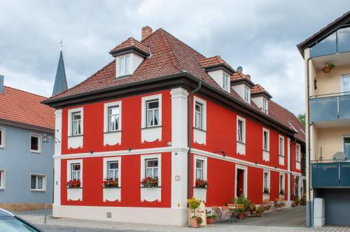 een rood-wit gebouw met bloemen op de ramen bij Hotel Schuberths am Markt in Buttenheim