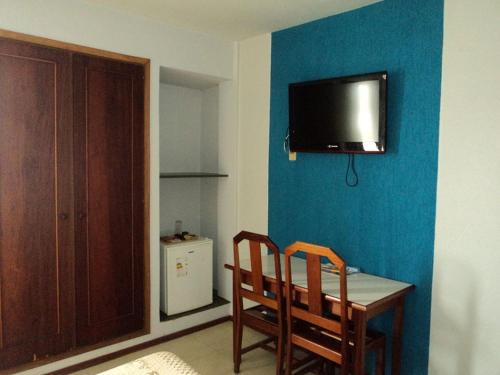 Habitación con mesa, 2 sillas y TV en la pared. en MAGA PLAZA HOTEL, en São José do Rio Pardo