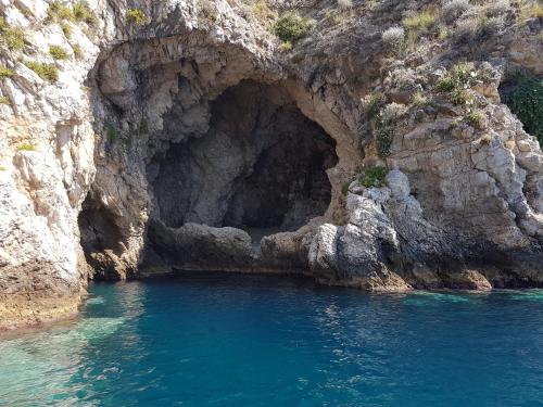 a cave in the side of a cliff with blue water at La Casita Il Poggio Del Sole in Letojanni