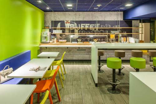 a fast food restaurant with colorful chairs and tables at ibis budget Leipzig Messe in Leipzig