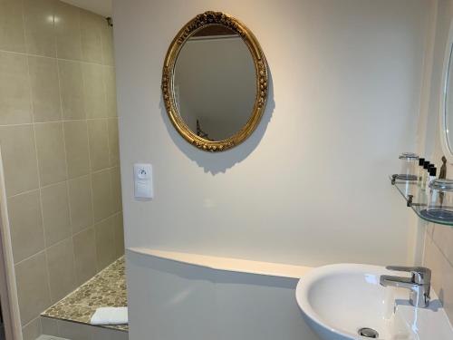 a bathroom with a sink and a mirror on the wall at Victoria Arromanches B&B in Tracy-sur-Mer