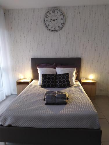 twee handdoeken op een bed met een klok aan de muur bij Zen attitude Appt 127 in Sens