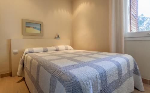 ein Schlafzimmer mit einem Bett mit einer blauen und weißen Decke in der Unterkunft Cliper A3 in Llafranc