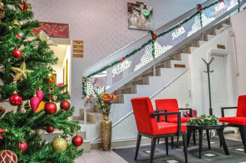 a christmas tree in a store with red chairs and a staircase at Garni hotel Alma in Pirot