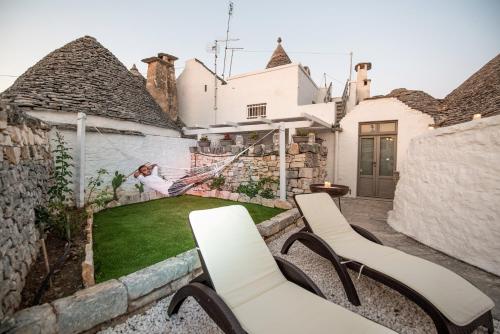 a woman sitting on a hammock in a backyard at Trulli Holiday Deluxe & Wellness in Alberobello