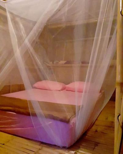 a bed covered in mosquito nets on a wooden floor at Bamboo Bungalow Baan Tai Phangan in Ban Tai