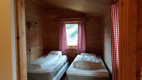twee bedden in een kleine kamer met een raam bij Leilighet 2240 in Haugsvær