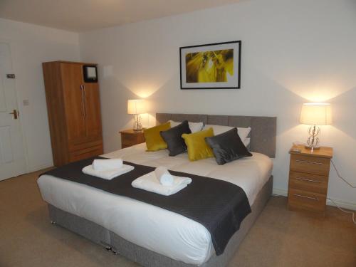 een slaapkamer met een groot bed met gele en zwarte kussens bij Redmarley House by Cliftonvalley Apartments in Cheltenham