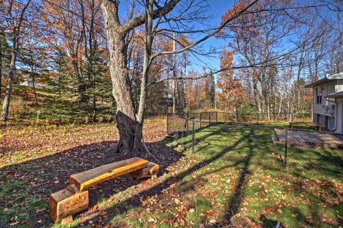 a wooden bench under a tree in a yard at Quaint Duluth Hideaway with Private Fenced-In Yard! in Duluth