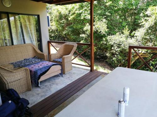 a porch with wicker chairs and a bench on a deck at Nkumbe 7C in Ponta Malangane