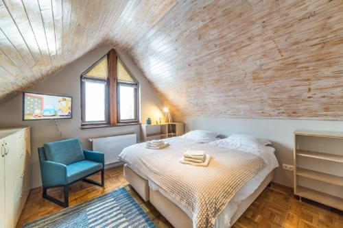 ein Schlafzimmer mit einem Bett und einem blauen Stuhl in der Unterkunft Casa Stella - spacious central villa in Cluj-Napoca