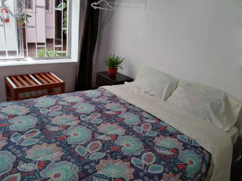 a bedroom with a bed with a colorful blanket and a window at Hotel Via Morburg in Nazca