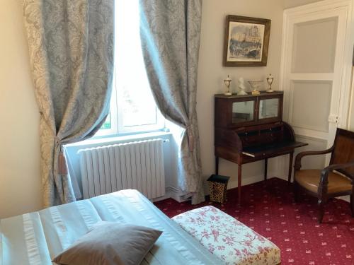 a bedroom with a bed and a desk and a window at Victoria Arromanches B&B in Tracy-sur-Mer