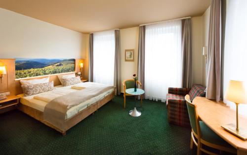 a hotel room with a bed and a desk at Akzent Waldhotel Rheingau in Geisenheim