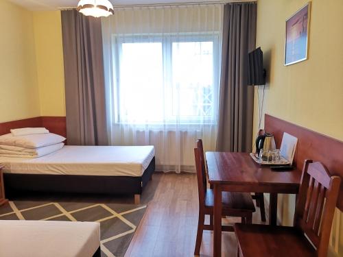 華沙的住宿－Hotel Duka，客房设有两张床、一张桌子和一扇窗户。