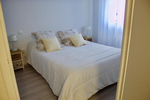 een slaapkamer met een bed met witte lakens en kussens bij Appart Chrystal in Carcassonne